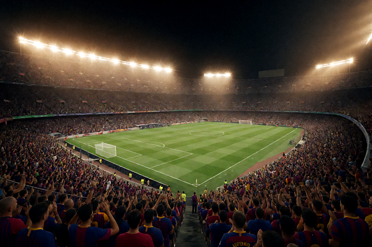 夜晚灯光下的大型足球场全景，观众席坐满球迷，比赛即将开始